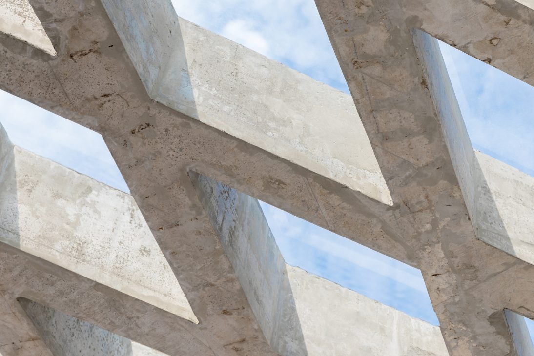 Estrutura de concreto geométrica sob céu azul, destacando linhas e formas arquitetónicas modernas.