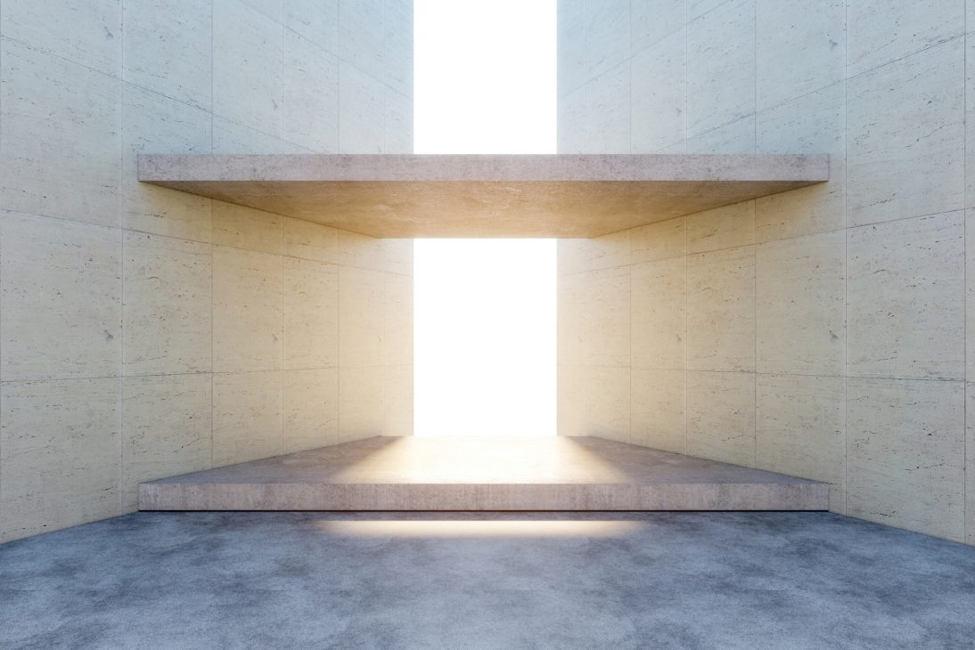 Espaço minimalista de arquitetura moderna com paredes de concreto e luz natural intensa ao fundo.